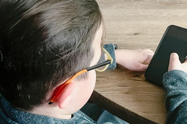 Kind met smartphone aan tafel